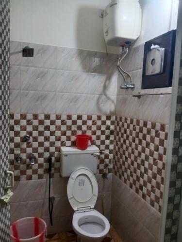 a bathroom with a toilet with a red bowl on it at Little Mount nest in Trivandrum