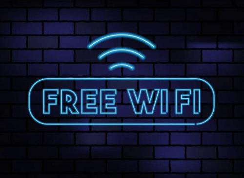 a neon sign with a free wifi sign on a brick wall at Airport Inn & Spa Manchester in Wilmslow