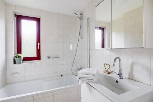 a white bathroom with a tub and a sink at Boomklever I Charmante Vakantiewoning met Openhaard in Zwiggelte