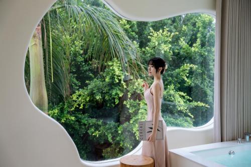 a woman standing in front of a window in a bathroom at 礼橖LoveTime·美学海景民宿（较场尾大鹏所城店） in Shenzhen