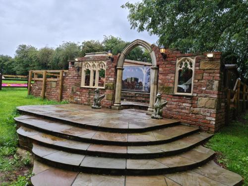 a stone structure with an arch and stairs in a yard at Burtree Country House, Tipi's, Treehouse & Lodge & house rooms with hot tubs in a private garden in Thirsk