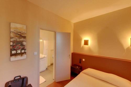 Habitación de hotel con cama y espejo en Le Tournedos, en Lézignan-Corbières