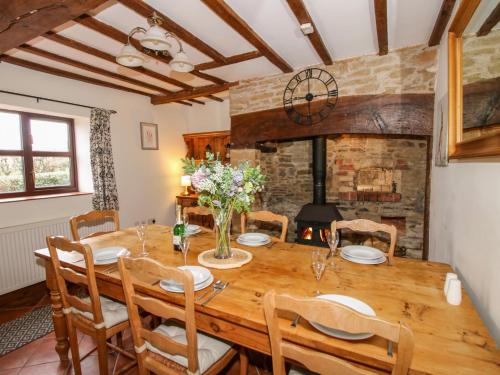 a dining room with a wooden table and chairs and a fireplace at Wilstone Cottage in Church Stretton