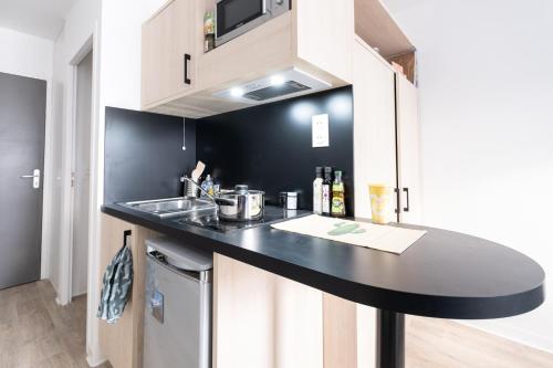 - une cuisine avec un plan de travail noir et un évier dans l'établissement Appartement cosy, à Bagneux