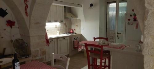 Una cocina con encimera y una mesa y sillas rojas. en Trullo Vito with pool, en Martina Franca