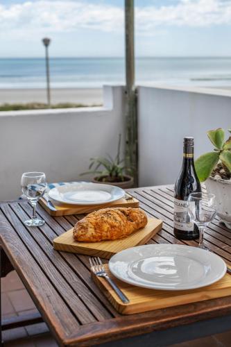 a wooden table with plates of food and a bottle of wine at Die Pomphuisie in Paternoster