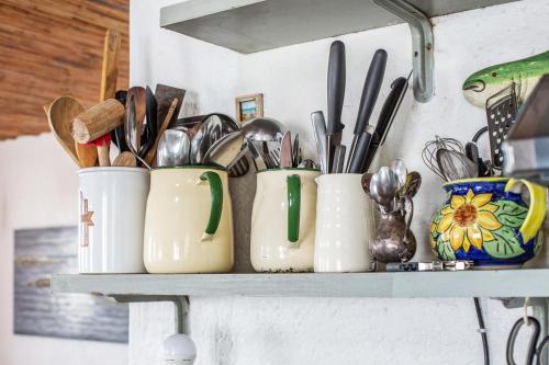 a shelf with several pots and spoons and utensils at Die Pomphuisie in Paternoster