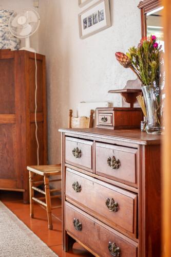a dresser with a vase of flowers on top of it at Die Pomphuisie in Paternoster