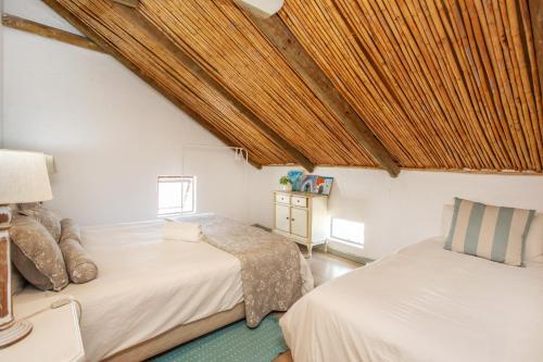a bedroom with two beds and a wooden ceiling at Die Pomphuisie in Paternoster