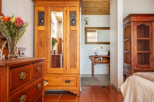 a bedroom with a dresser with a vase of flowers on it at Die Pomphuisie in Paternoster