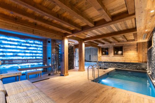 - une piscine dans une maison dotée d'un plafond en bois dans l'établissement Chalet KALINKA, MERIBEL,15 PERSONNES, PISCINE, SPA, MASSAGE, CINEMA ET PLAYROOM, à Les Allues