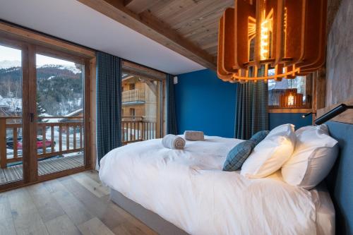 une chambre avec un grand lit et un balcon dans l'établissement Chalet KALINKA, MERIBEL,15 PERSONNES, PISCINE, SPA, MASSAGE, CINEMA ET PLAYROOM, à Les Allues