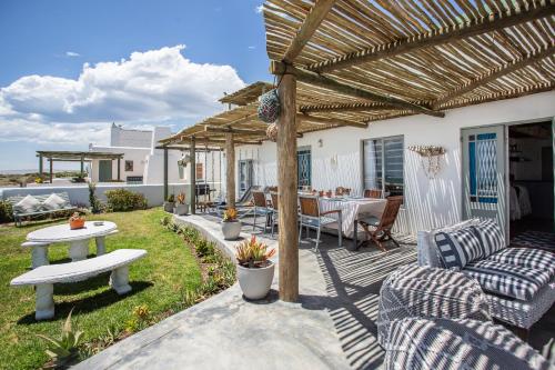 a patio with a table and chairs and a pergola at Die Pomphuisie in Paternoster
