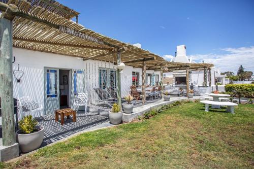 a house with a wooden pergola on a patio at Die Pomphuisie in Paternoster