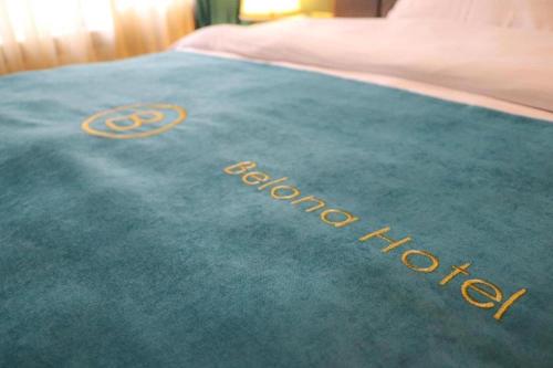 a bed with a green blanket with the word devoted at Belona Hotel in Kutaisi