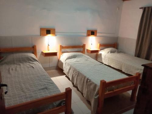 three beds in a room with lights on the wall at Chacra Don Joaquin 2 in La Cruz