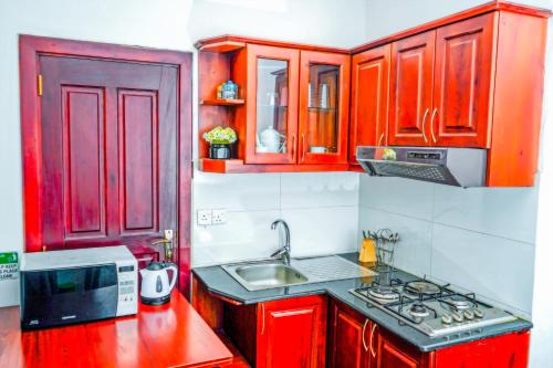 a kitchen with red cabinets and a sink at Mountain Breeze Chill Apartment in Nuwara Eliya