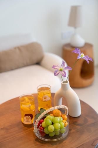 a table with a bowl of fruit and two glasses of juice at 礼橖LoveTime·美学海景民宿（较场尾大鹏所城店） in Shenzhen
