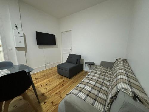 a bedroom with a bed and a chair and a television at Confort 6 pers & Wi-Fi rapide in La Courneuve