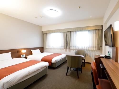 a hotel room with two beds and a television at Tokyo Inn in Tokyo