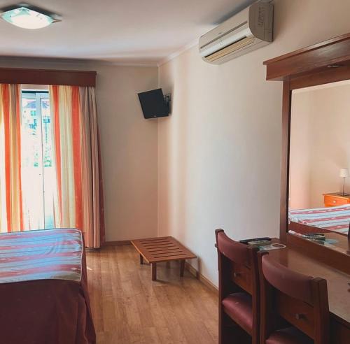 a bedroom with a bed and a table and a mirror at Residencial São José e Residencial Águas Santas in Termas de Sao Pedro do Sul