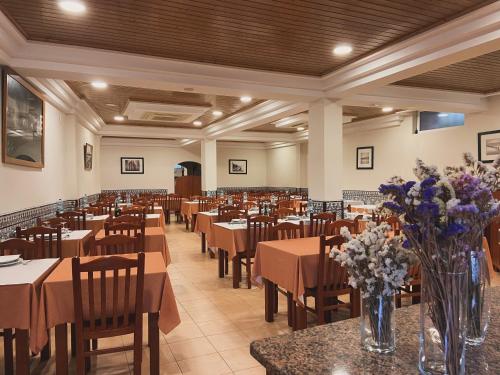 a restaurant with tables and chairs and flowers on tables at Residencial São José e Residencial Águas Santas in Termas de Sao Pedro do Sul