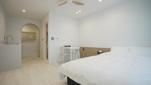 a white bedroom with a bed and a table at Stay Yongdam in Jeju