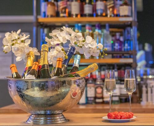a bowl of wine bottles and flowers on a table with glasses at Meon Valley Hotel, Golf & Country Club in Shedfield