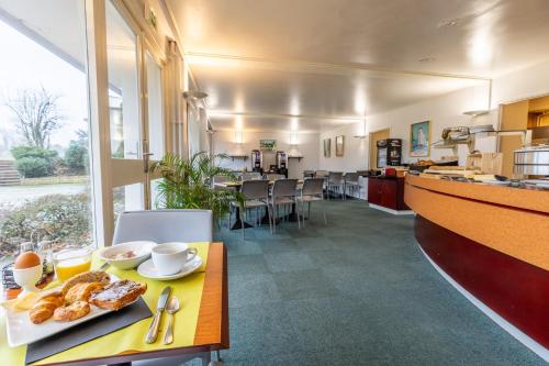 a cafeteria with a table with a plate of food at Brit Hotel Le Parc Vichy in Bellerive-sur-Allier