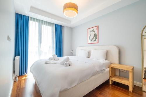 a white bedroom with a large white bed with blue curtains at Luxury Apartments in Ofton Residence in Istanbul