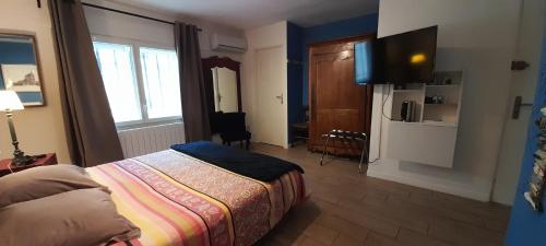 une chambre avec un lit et une télévision dans l'établissement Le jardin bernard PERRIER, à Montbazin