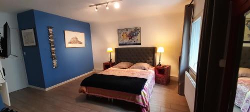 une chambre avec un lit avec un mur bleu dans l'établissement Le jardin bernard PERRIER, à Montbazin