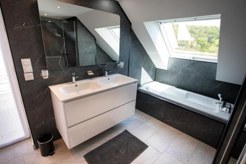 ein Badezimmer mit Waschbecken und Badewanne in der Unterkunft Manava Villa vue mer et Mont Saint Michel piscine intérieure in Saint-Jean-le-Thomas
