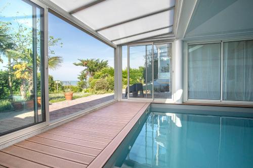 - une piscine vide dans une maison avec terrasse couverte dans l'établissement Manava Villa vue mer et Mont Saint Michel piscine intérieure, à Saint-Jean-le-Thomas