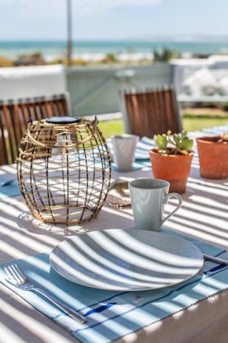 a table with plates and cups and a basket on it at Die Pomphuisie in Paternoster