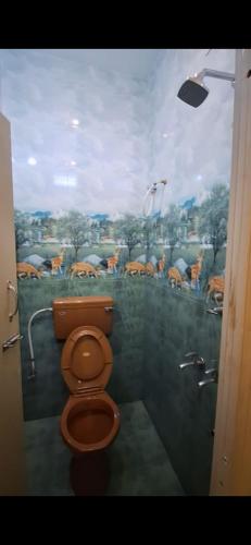 a bathroom with a toilet with a painting on the wall at Subramanya Residency in Thiruchendur