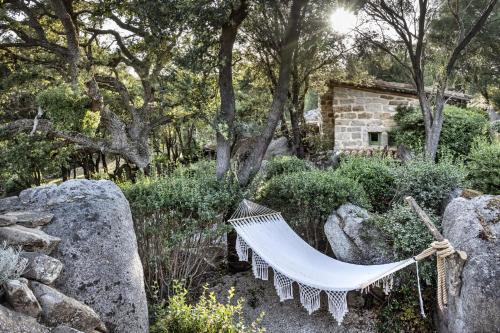 a hammock in a garden with trees and rocks at Gallicantu Stazzo Retreat in Luogosanto