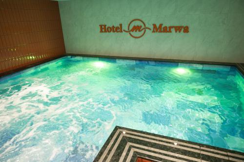 a large swimming pool in a building with a hotel mgma sign at Hotel Marwa Tashkent Pool&Spa in Tashkent