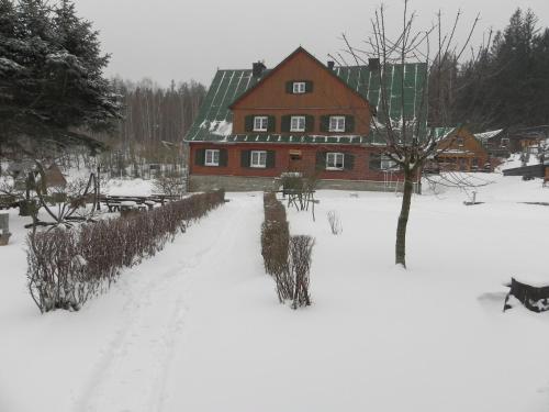 a snow covered yard with a large red house at Osada Chybotek in Przesieka