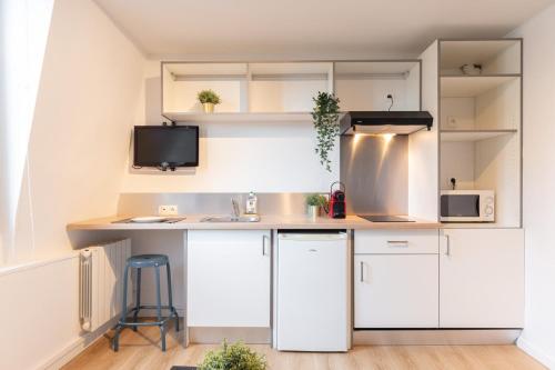 une cuisine avec des armoires blanches et un comptoir dans l'établissement Lille Hypercentre - Gares - Charmant duplex, à Lille