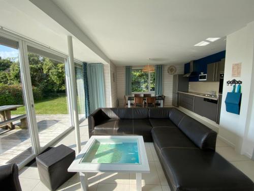 a living room with a black leather couch and a table at Résidence de Nodeven in Guissény