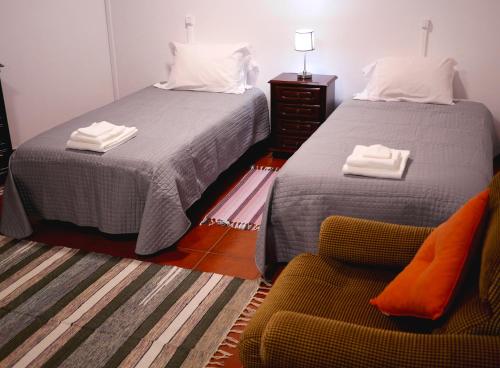 two beds in a room with a chair and a bed at Green Valley Cruzinhas House with Fireplace & BBQ in Santana