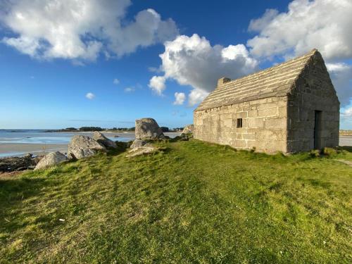 an old stone building on a grassy hill next to the water at Résidence de Nodeven in Guissény
