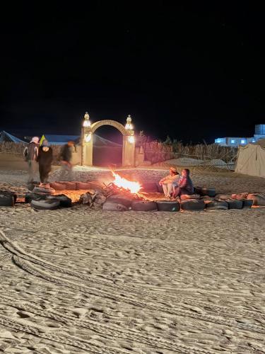 a group of people sitting around a fire on the beach at Camp Dunes Insolites Sabria in Sabria