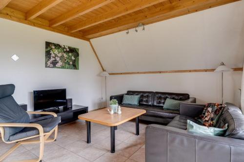 a living room with a couch and a table at Roerdomp I Vrijstaande Bungalow met Buiten Zitjes in Zwiggelte