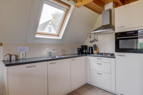 a kitchen with white cabinets and a window at Roerdomp I Vrijstaande Bungalow met Buiten Zitjes in Zwiggelte