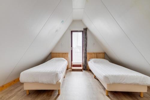 two beds in a attic room with a window at Roerdomp I Vrijstaande Bungalow met Buiten Zitjes in Zwiggelte