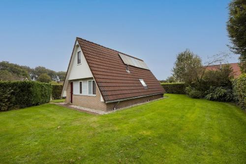 a small house with a large grass yard at Roerdomp I Vrijstaande Bungalow met Buiten Zitjes in Zwiggelte