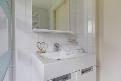 a white bathroom with a sink and a mirror at Roerdomp I Vrijstaande Bungalow met Buiten Zitjes in Zwiggelte
