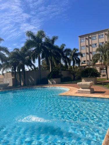 a large swimming pool with palm trees and a building at Condado Hotel Casino Santo Tome in Santo Tomé